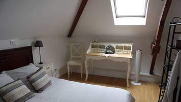 A bedroom with a bed, a desk, a chair, and a skylight.