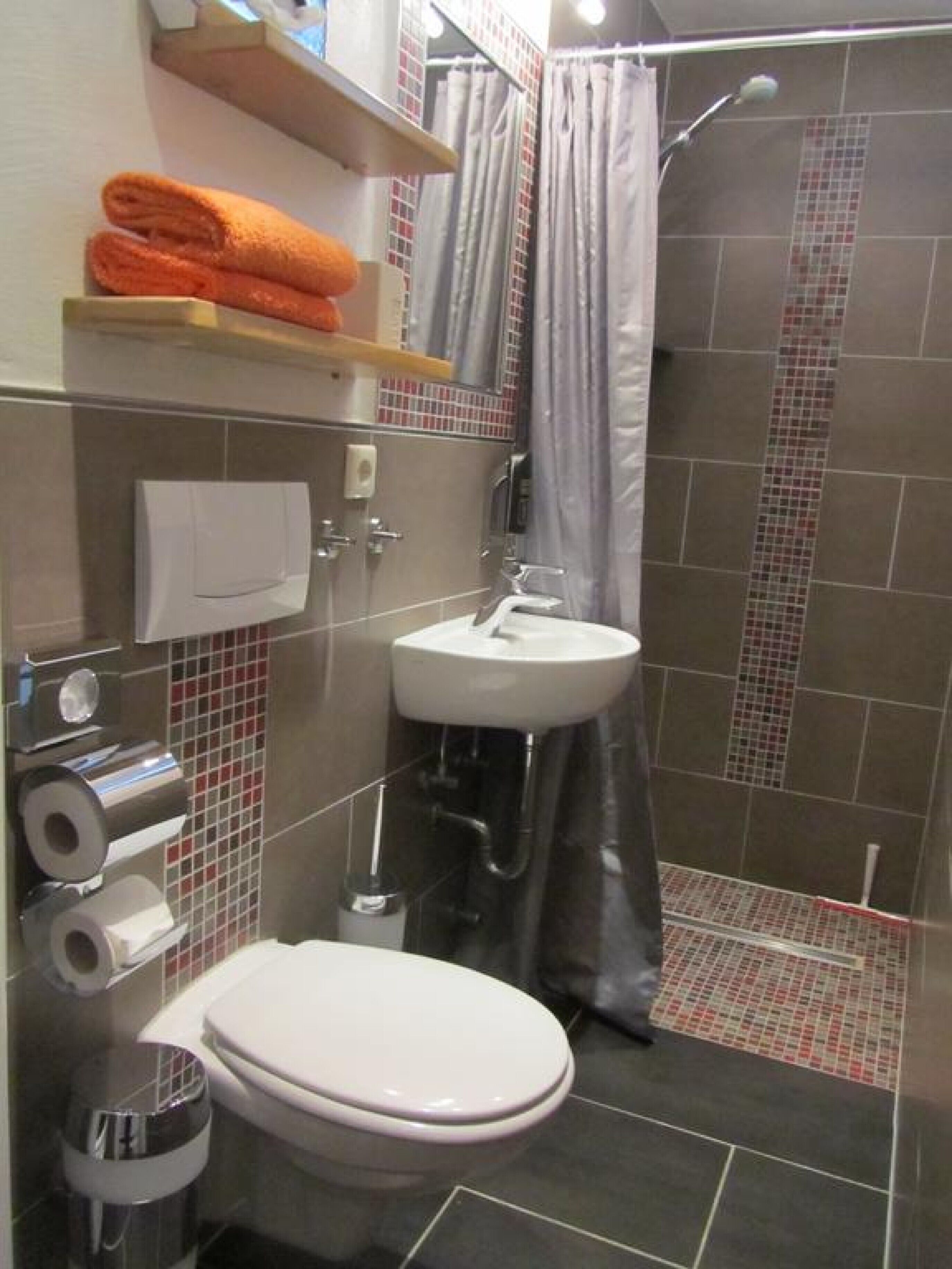 A modern bathroom with a toilet, sink, and shower.