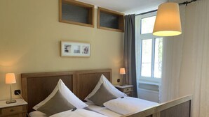 Ein ordentlich bezogenes Bett mit einem Holz-Kopfteil, zwei Nachttischlampen und einem gerahmten Bild darüber.
