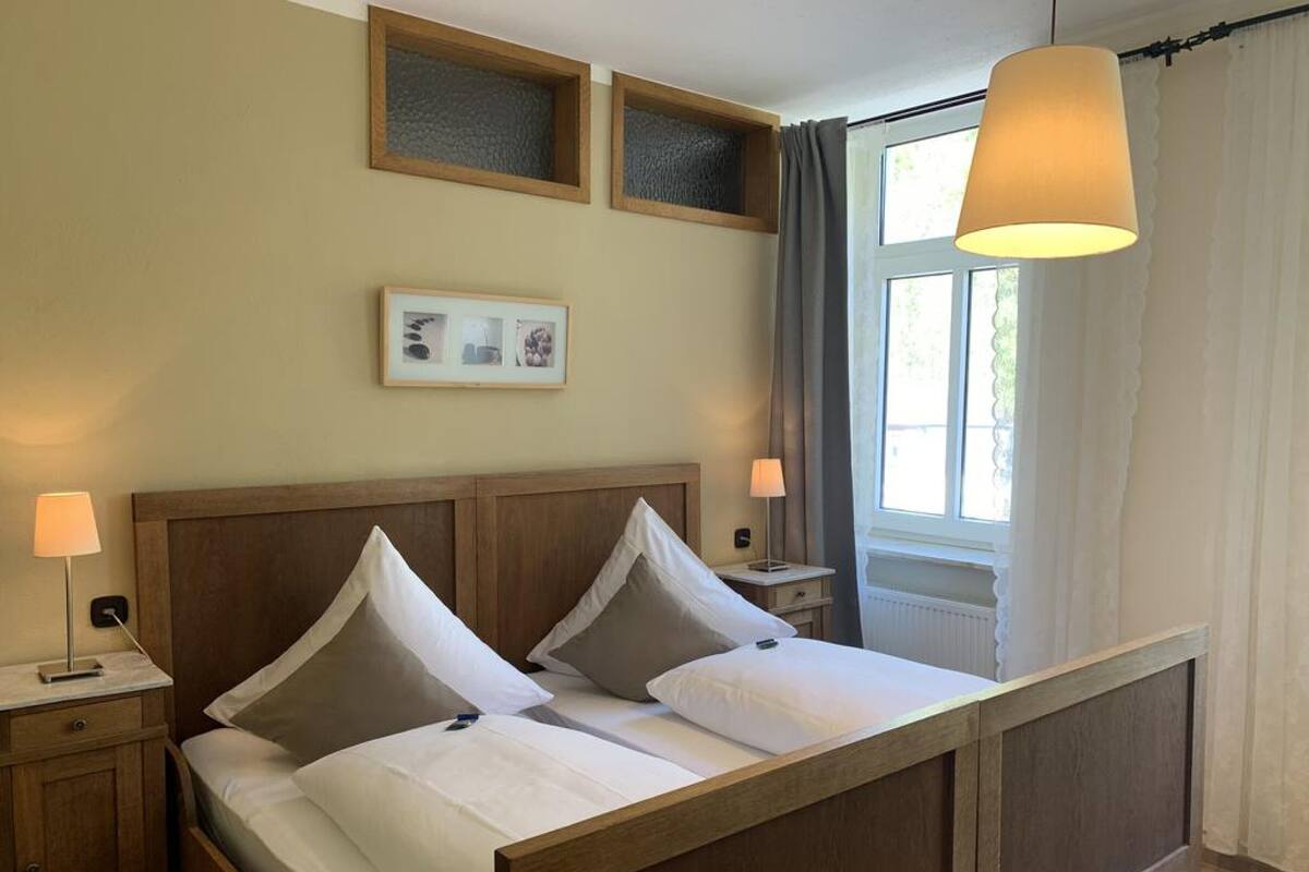 A neatly made bed with a wooden headboard, two bedside lamps, and a framed picture above the bed.
