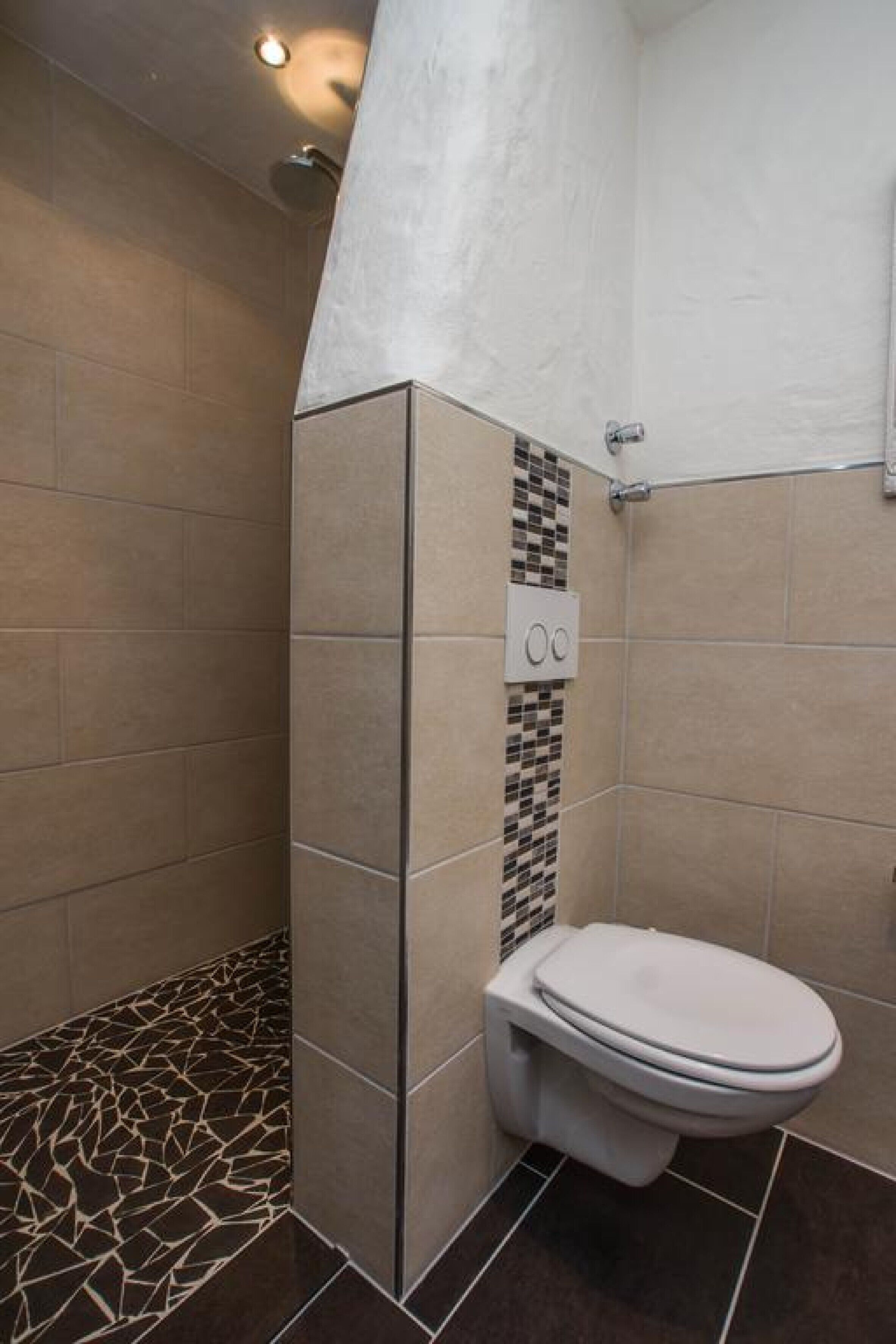Un baño con inodoro, ducha y suelo de baldosas.