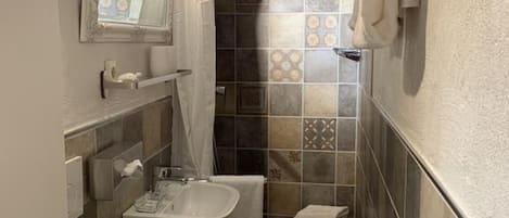 Casa de banho compacta com sanita, lavatório e zona de duche.