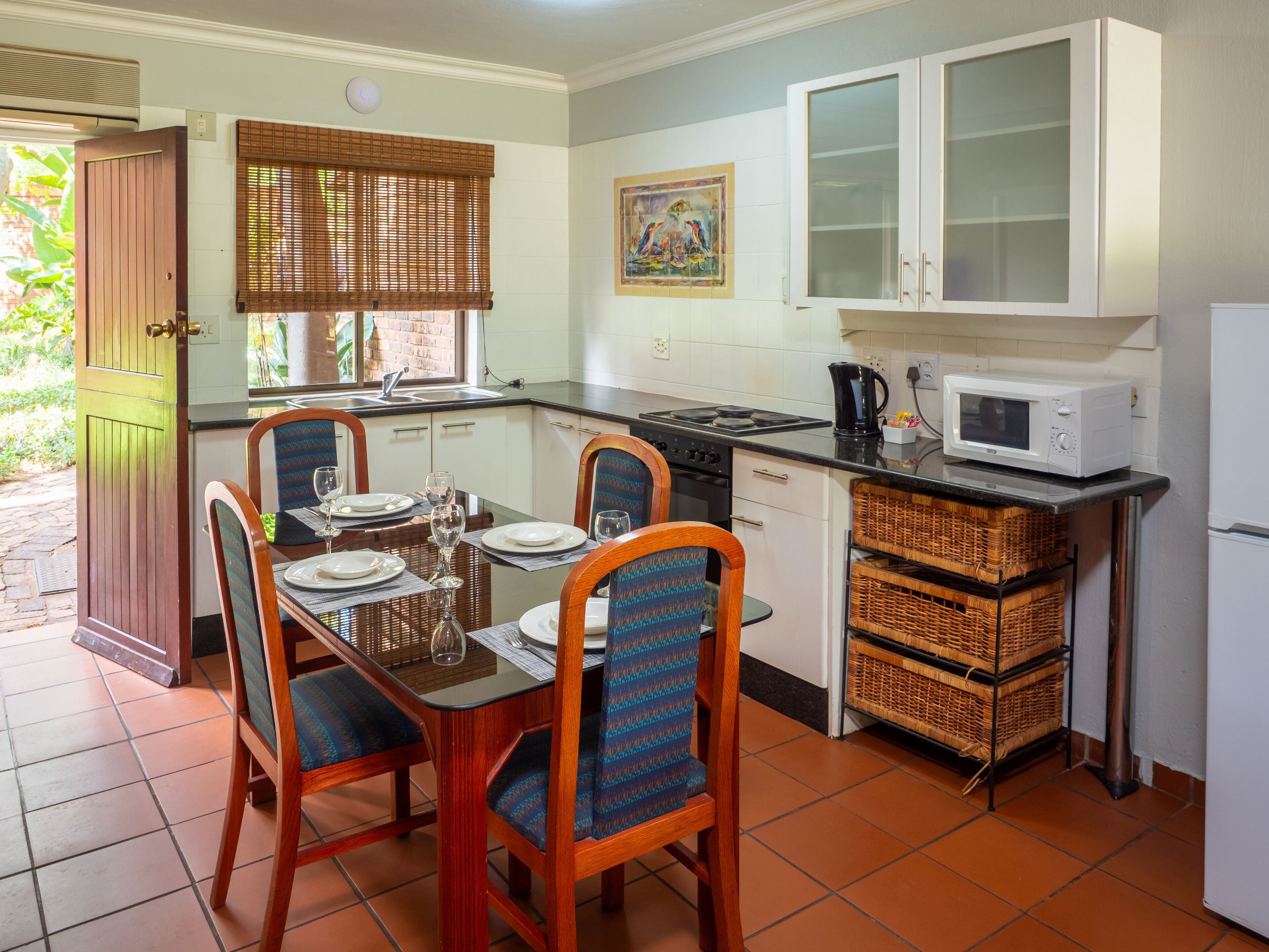 A compact kitchen with a dining area, featuring a stove, microwave, and cabinets.