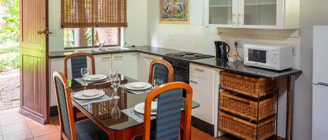 A compact kitchen with a dining area, featuring a stove, microwave, and cabinets.