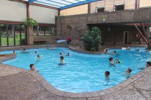 Una piscina interior con varias personas nadando y jugando.
