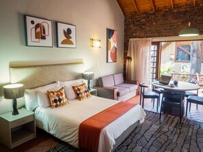 Habitación de hotel con cama, sofá, una mesa con una computadora portátil y vistas al exterior.
