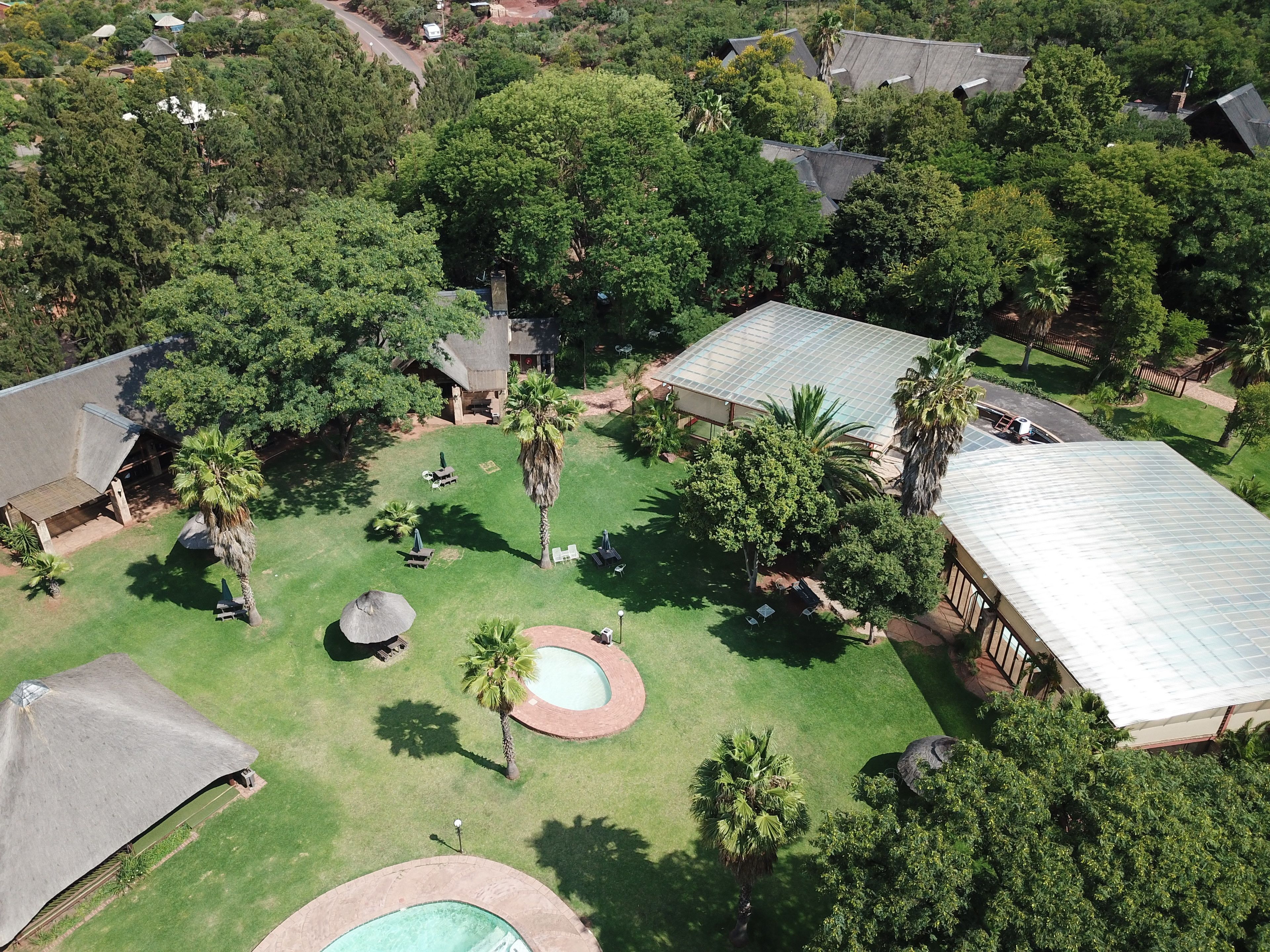 Vista aérea de uma área residencial com várias casas, uma piscina e um gramado bem cuidado.