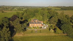 A large, rectangular brick building surrounded by dense trees, with a paved driveway and a small garden area in front. - The Upper House (Stoke-on-Trent)