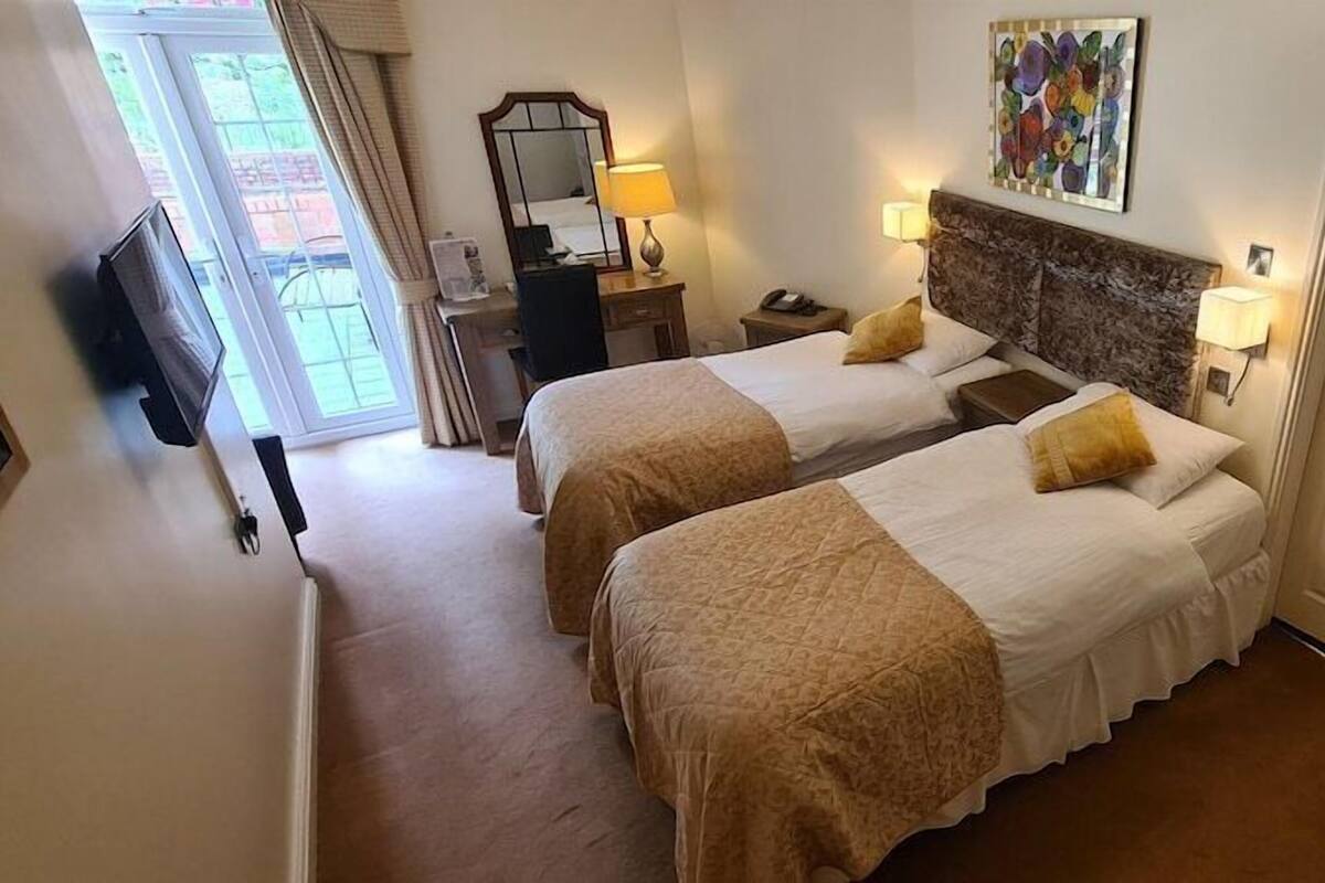 A hotel room with two beds, a television, a desk, and a door.