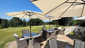 An outdoor patio with wicker furniture and large umbrellas. - The Upper House (Stoke-on-Trent)