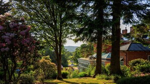A garden with a conservatory, trees, and a building with a green roof. - The Upper House (Stoke-on-Trent)