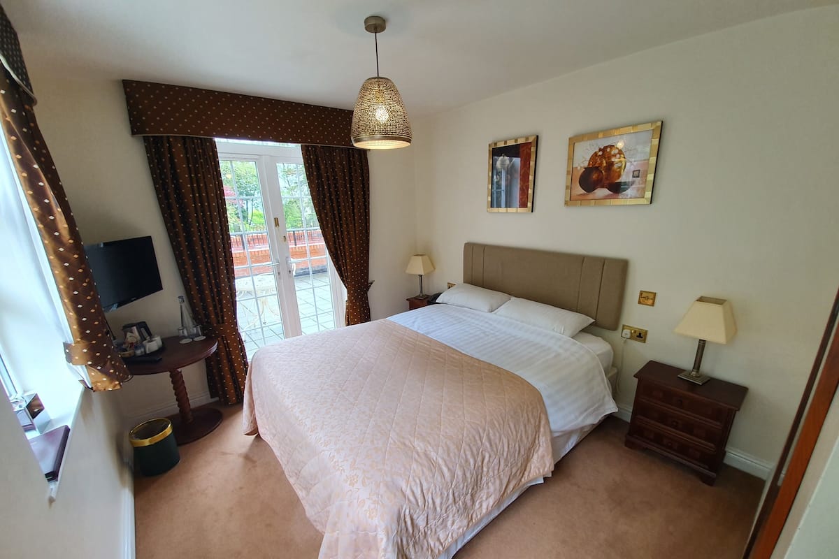 A hotel room with a large bed, a desk with a computer, a TV, and a view of the outdoors.