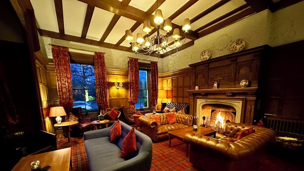 A cozy room with a fireplace, leather sofas, and a plaid carpet. - The Upper House (Stoke-on-Trent)