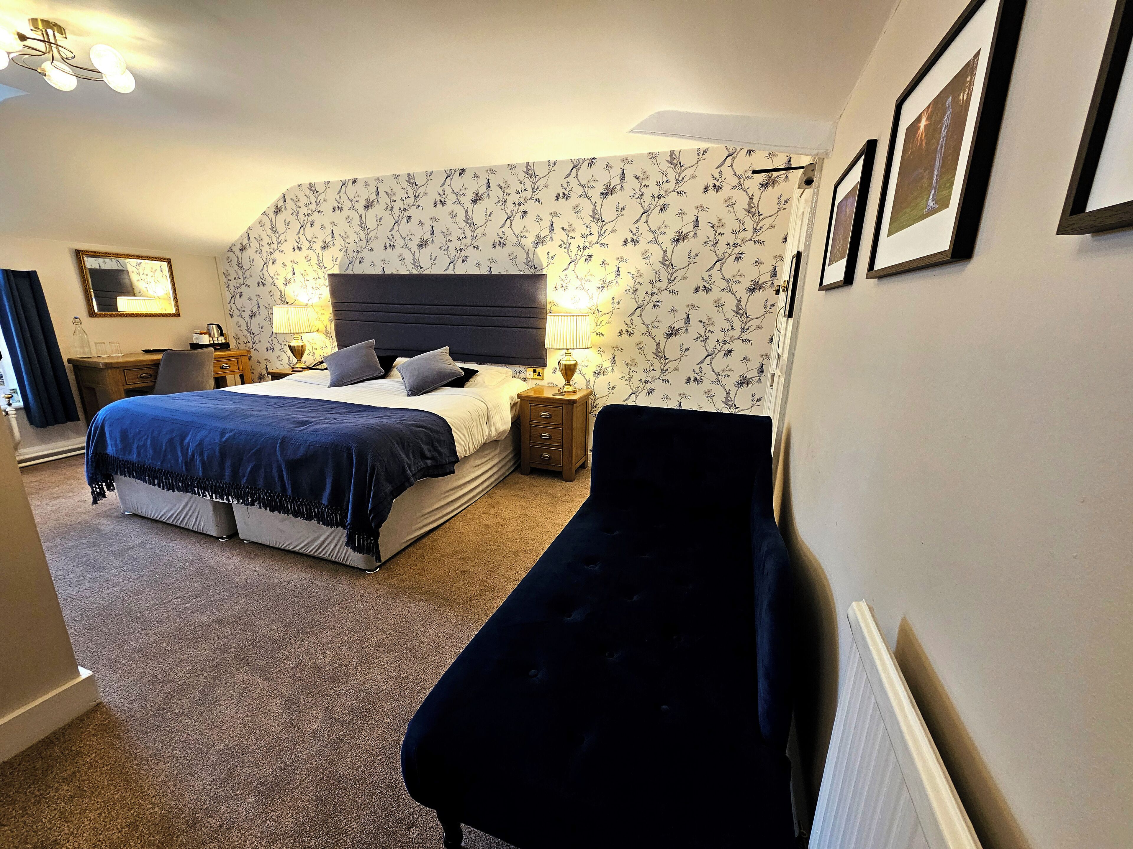 A bedroom with a bed, bedside tables, a desk, and a chair.
