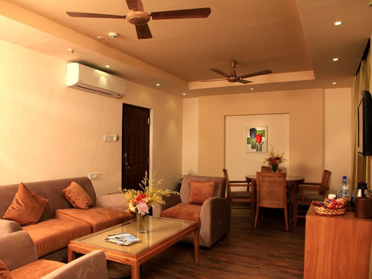 A modern living room with a sofa, coffee table, and a dining area with chairs and a table.