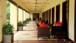 A corridor with wicker furniture, ceiling fans, and potted plants. - Country Roads (Uluberiya)