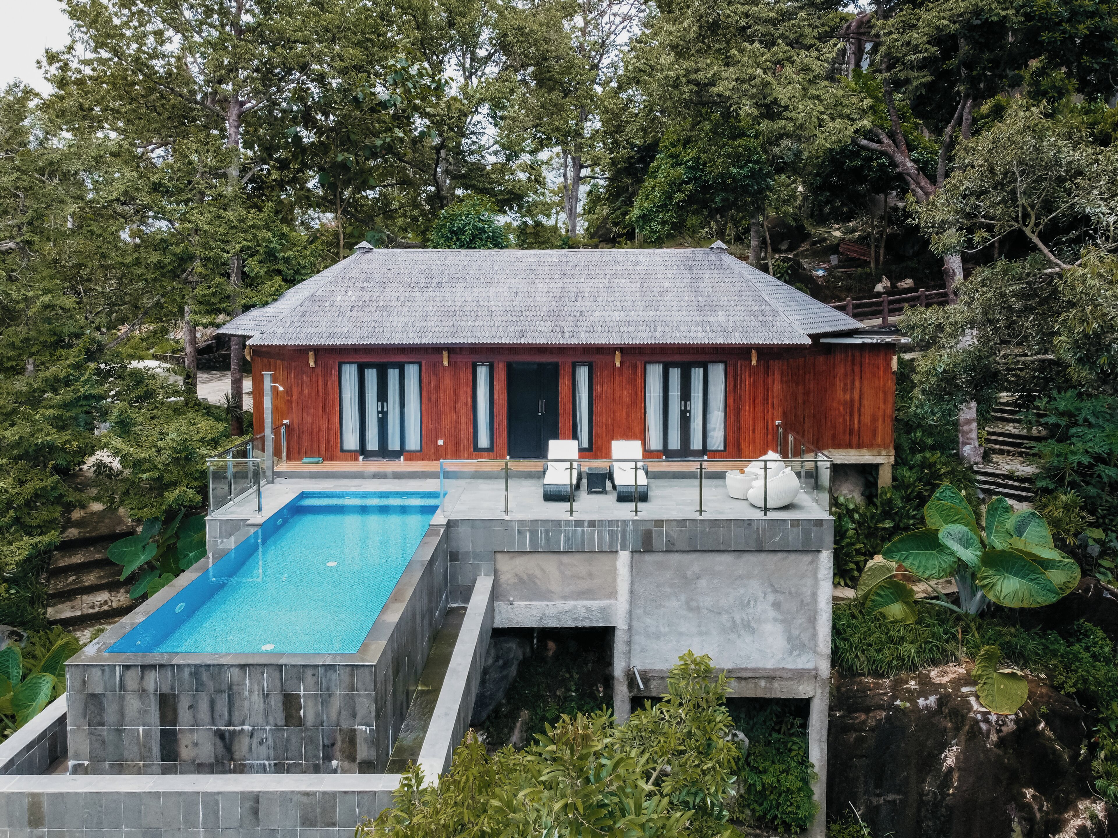 Una casa moderna con piscina, fachada de madera y ventanas grandes.