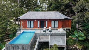 Una casa moderna con piscina, fachada de madera y ventanas grandes.