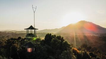 Un pabellón con una antena de radio, rodeado de árboles frondosos y una montaña al fondo.