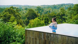 Una persona de pie en la azotea, con vistas a un bosque denso.