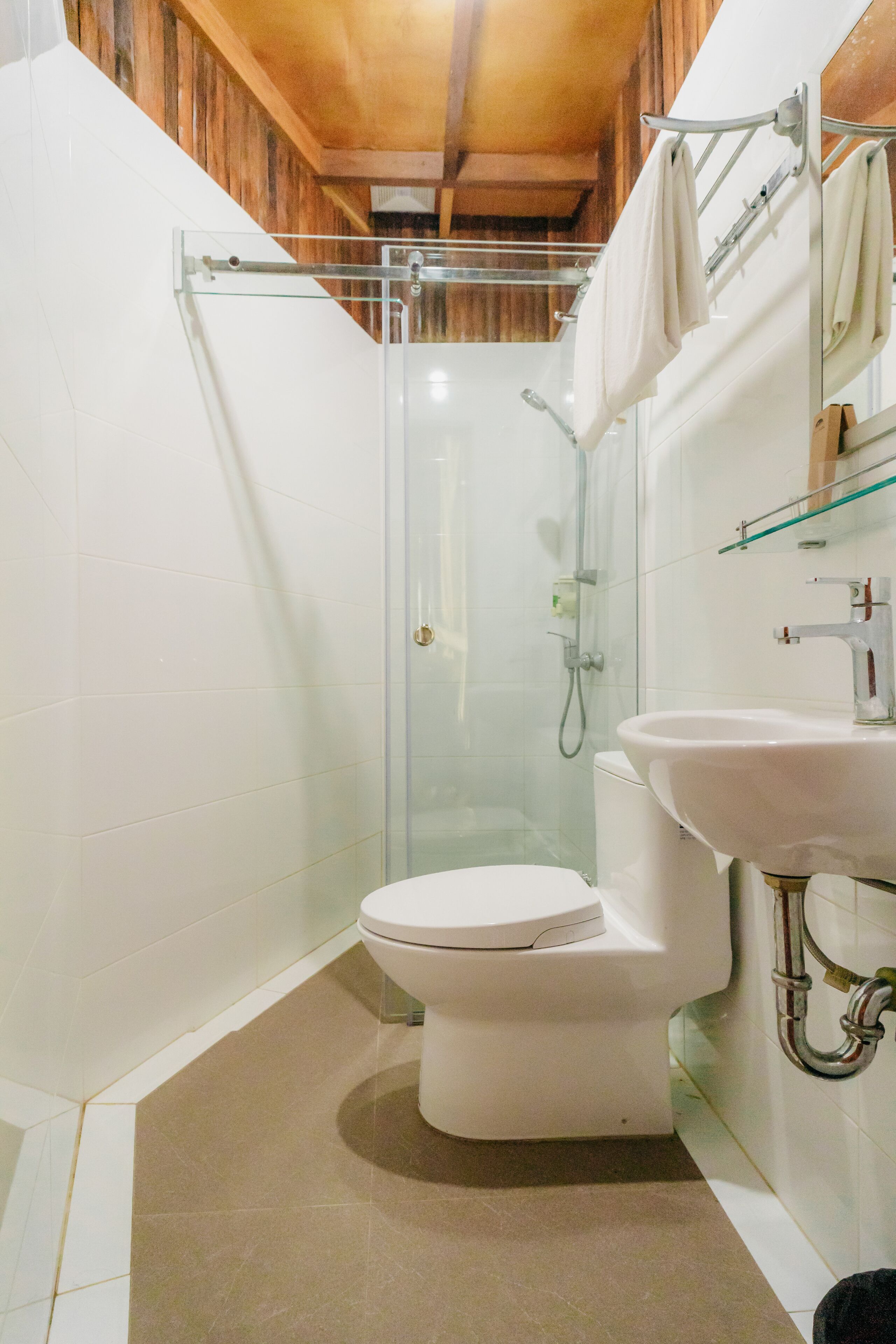 A modern bathroom with a glass-enclosed shower, a white toilet, and a sink with a mirror above it.