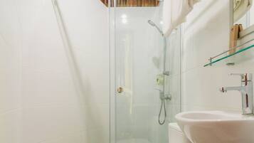 A modern bathroom with a glass-enclosed shower, a white toilet, and a sink with a mirror above it.