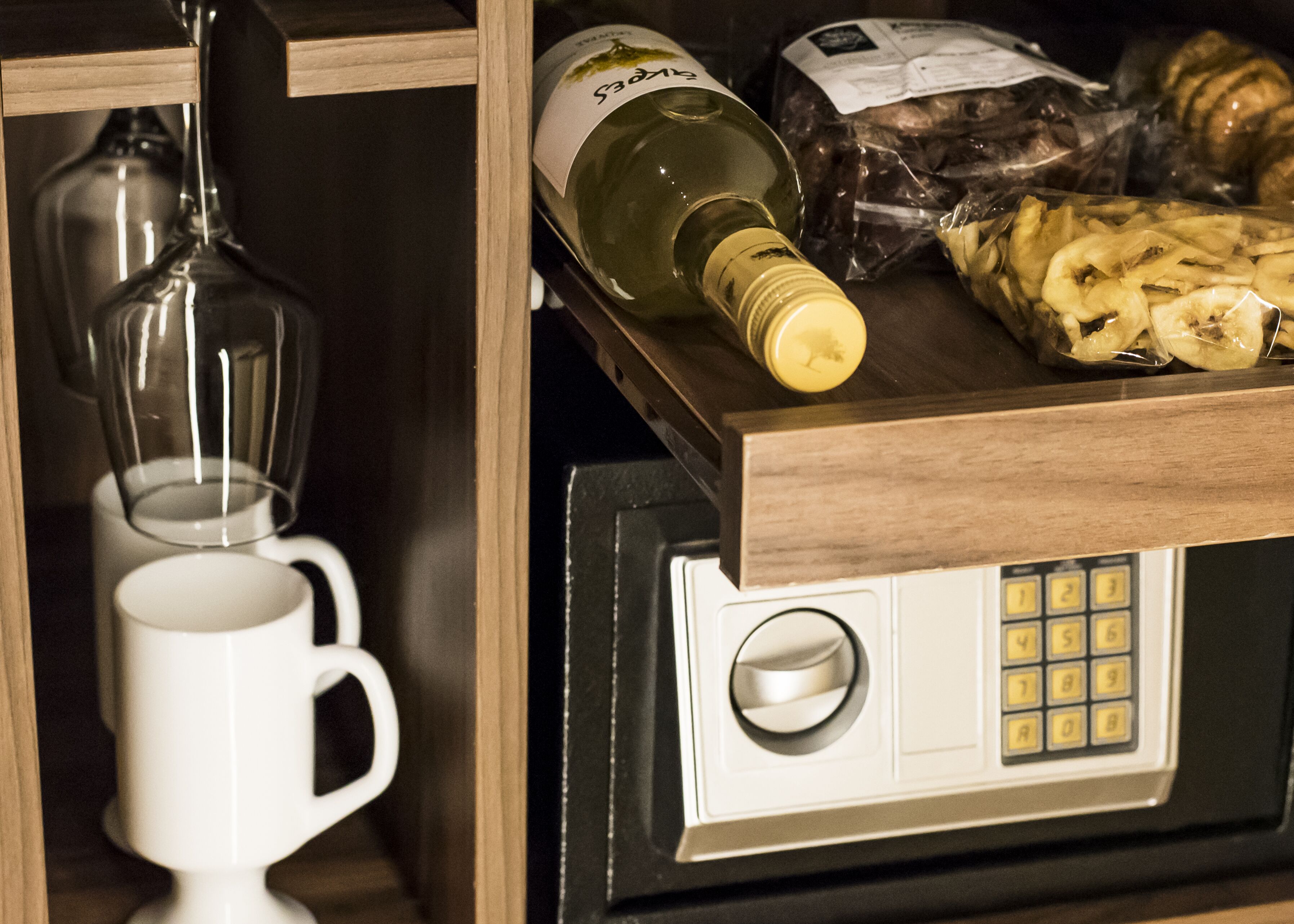 A kitchen area with a microwave, a wine bottle, and a bag of snacks.