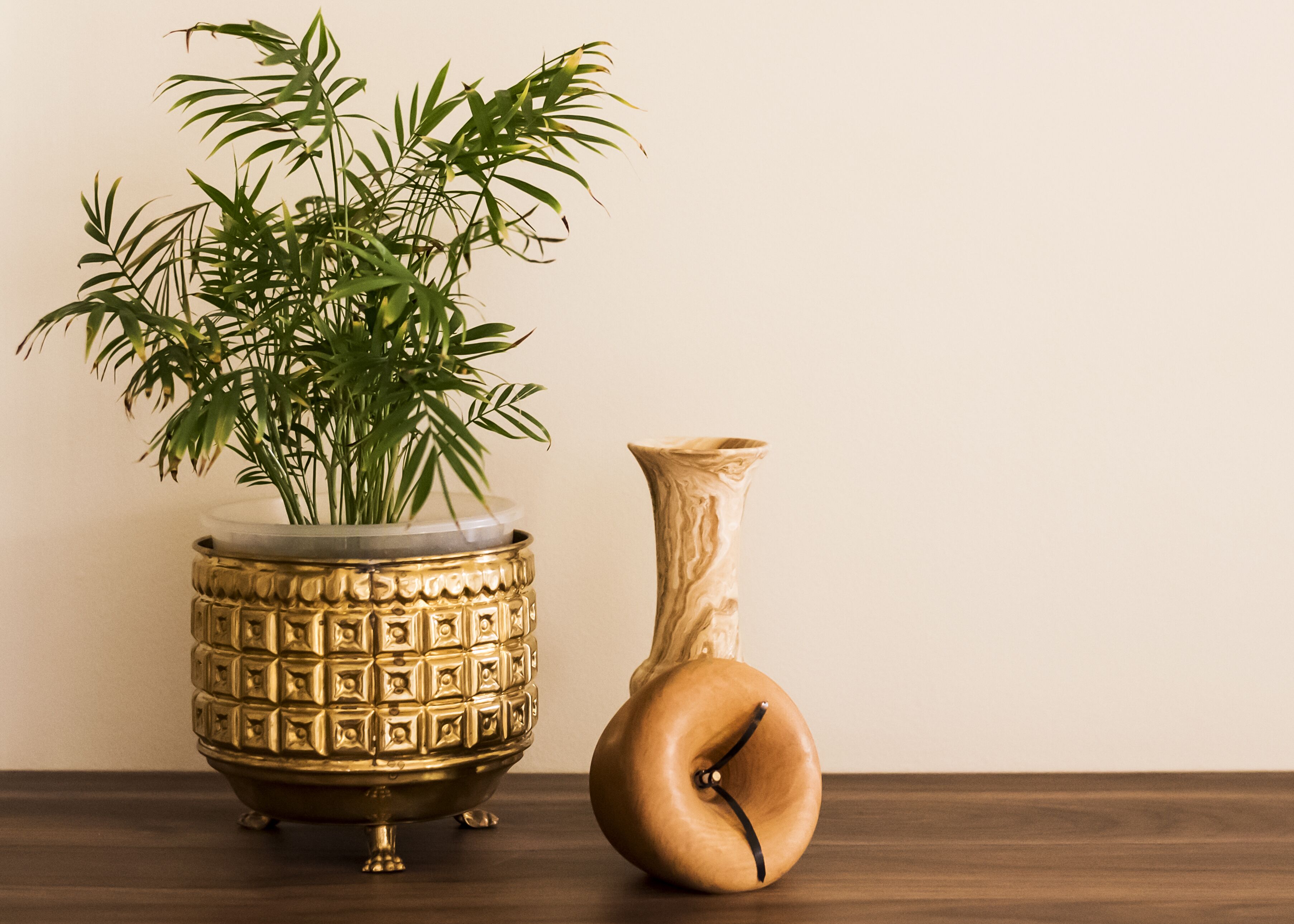 Un vase décoratif doré contenant une plante dans un récipient en verre transparent.
