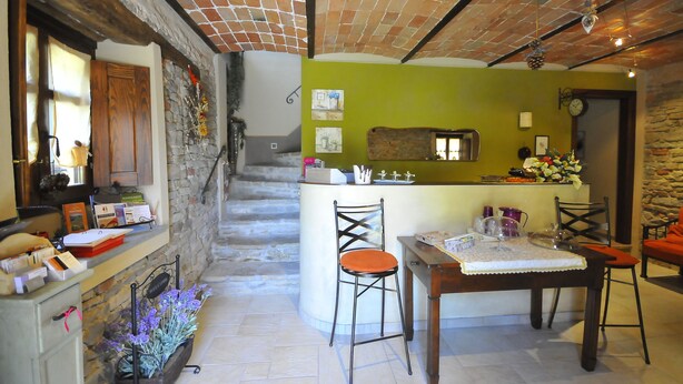 A cozy interior with a stone staircase, a dining area with a table and chairs, and a kitchen counter with various items. - B&B Cà Pavaglione (Castino)