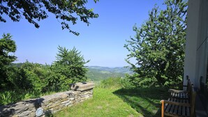 A stone wall with a bench, overlooking a scenic landscape with trees and a clear sky. - B&B Cà Pavaglione (Castino)