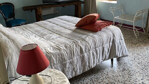 A bedroom with a bed, a TV, a table, and a chair. - B&B Cà Pavaglione (Castino)
