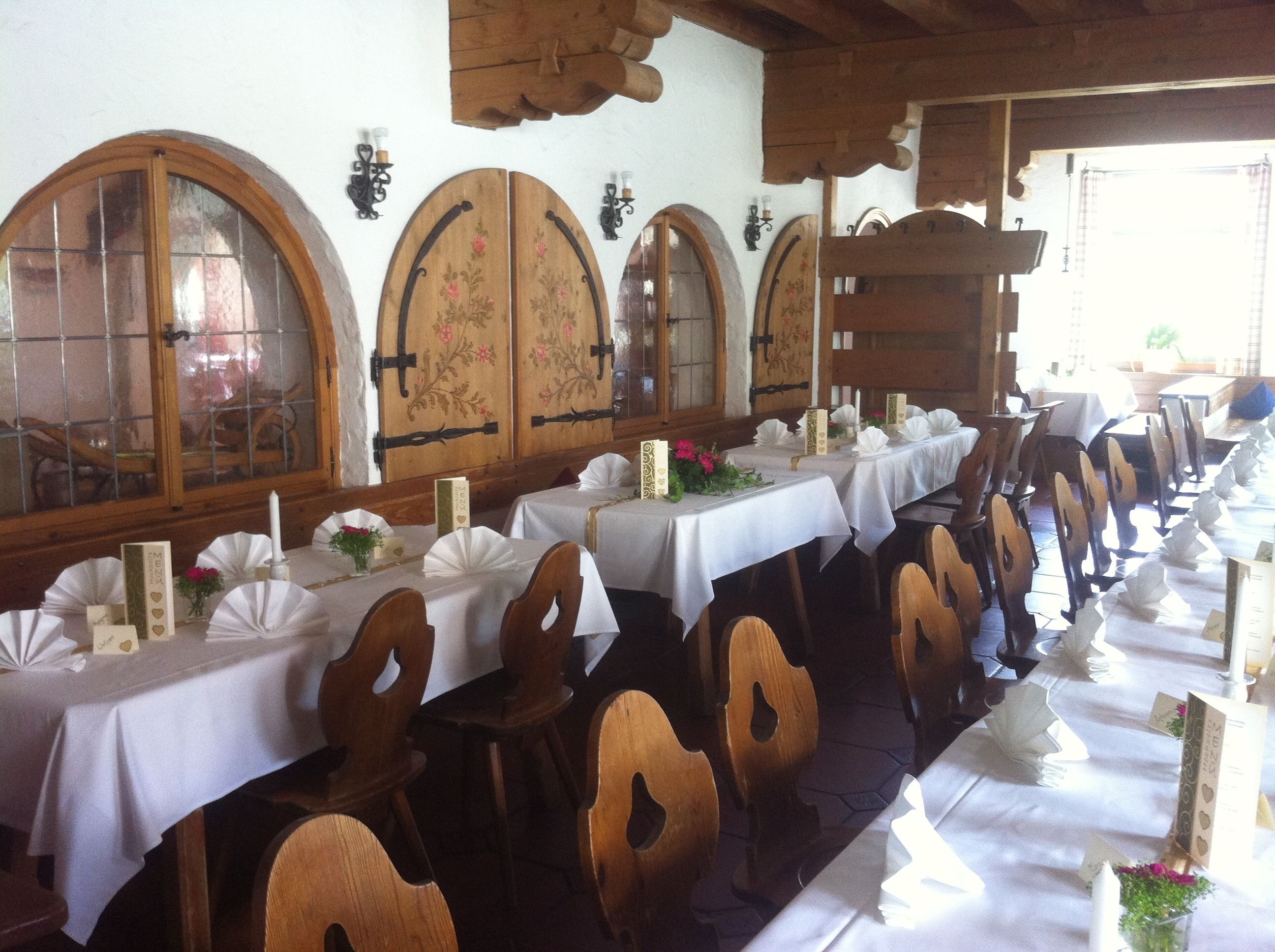 Une longue table à manger recouverte de nappes blanches, avec des chaises en bois et des centres de table floraux.