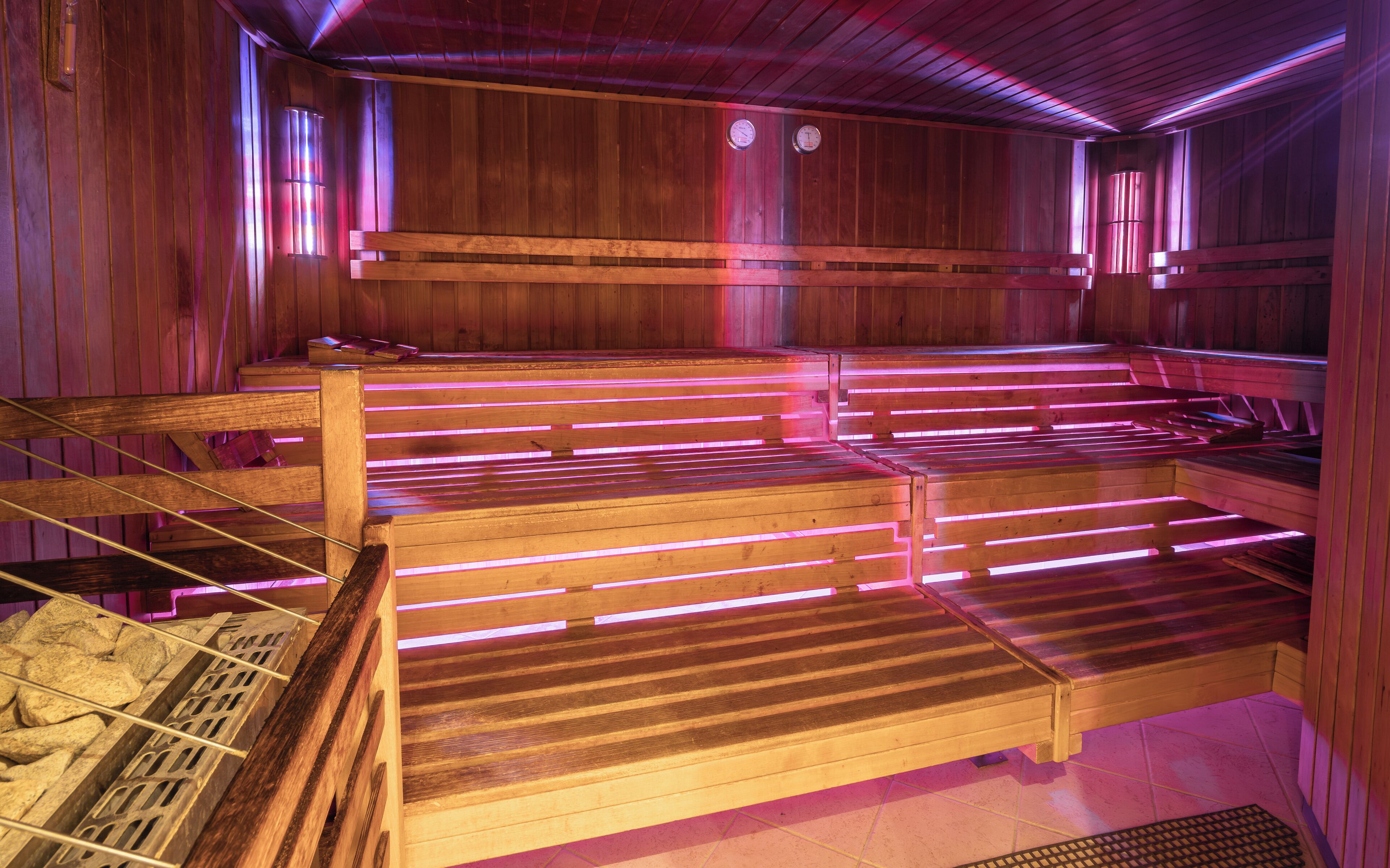 A sauna with wooden benches and benches, wooden walls, and a tiled floor.
