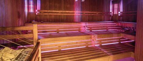 A sauna with wooden benches and benches, wooden walls, and a tiled floor.