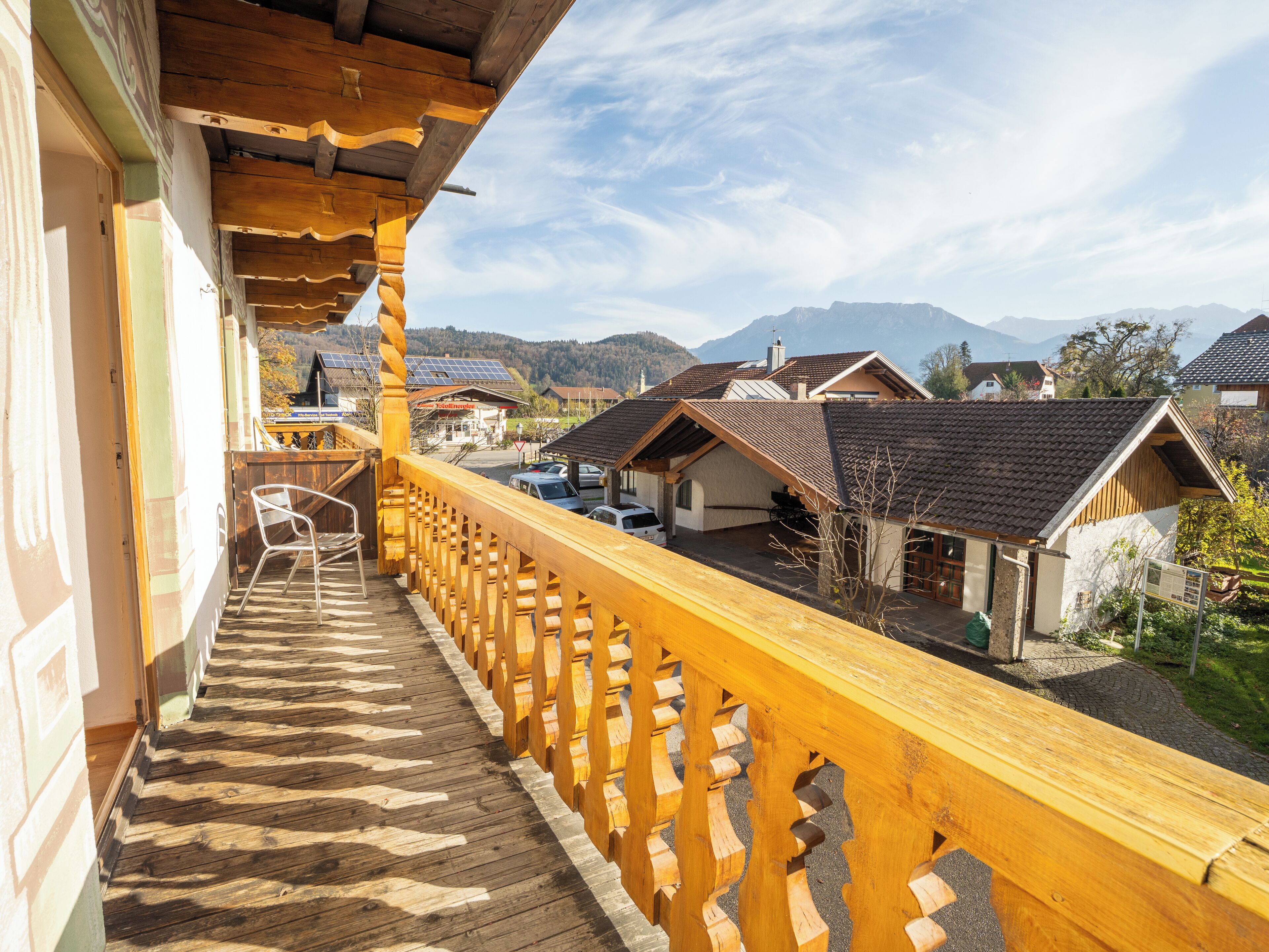 A wooden balcony with a view of houses and mountains.