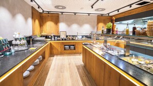 A modern kitchen with wooden cabinets, a central island, and various food items displayed on the counter. - Hotel Gasthof Metzgerei Keindl (Oberaudorf)