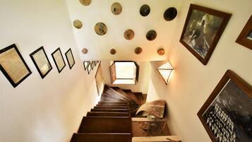 Una escalera con certificados enmarcados en la pared, un cuadro enmarcado y una lámpara decorativa.