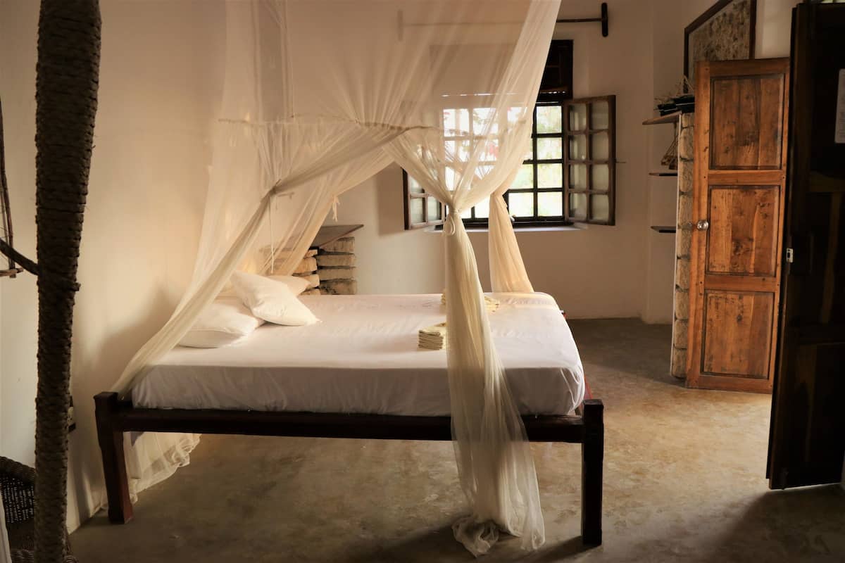 Una habitación con una cama bajo un dosel, un armario de madera y una ventana con vistas.