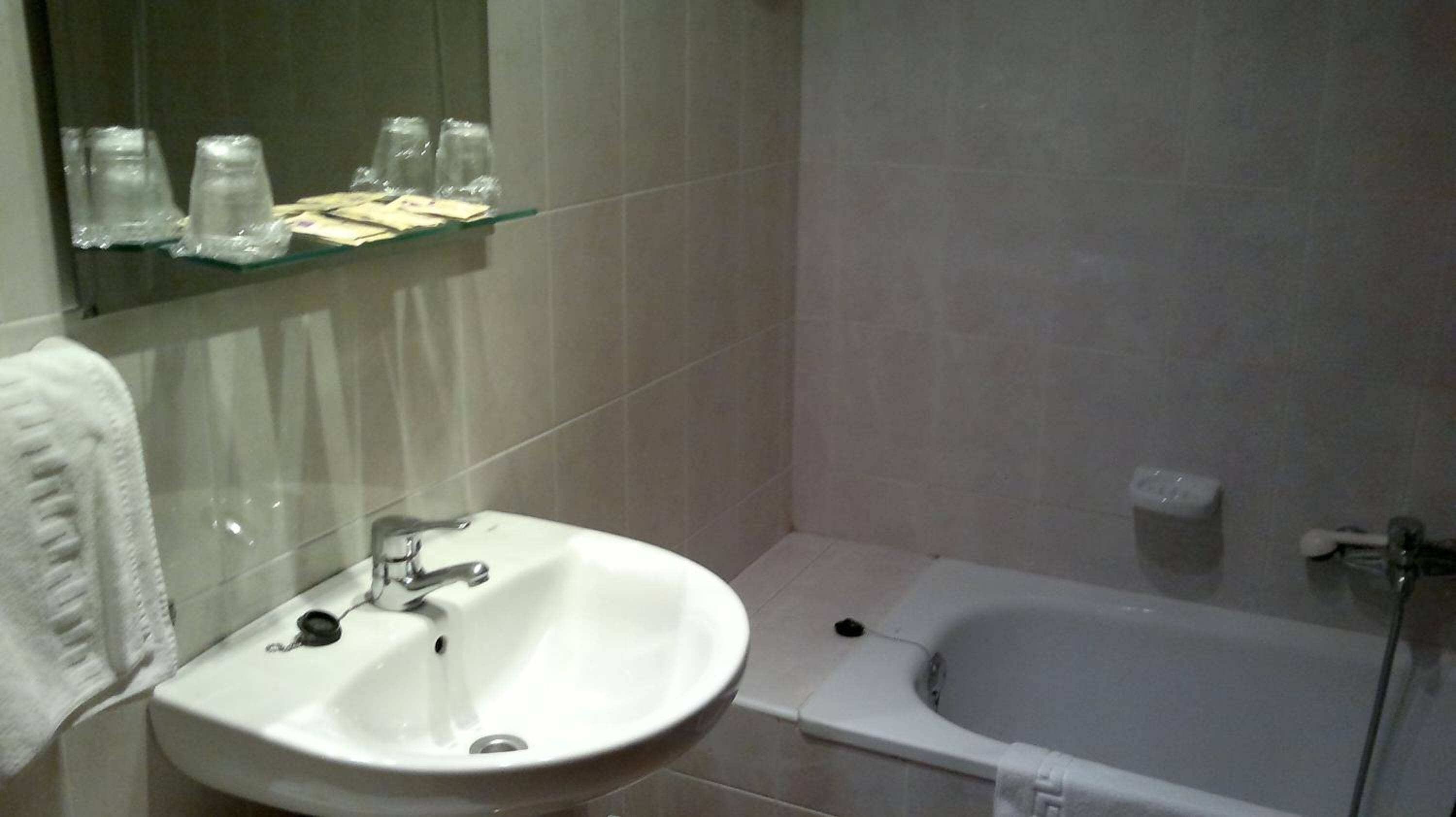 A bathroom with a white sink, a mirror, and a bathtub.