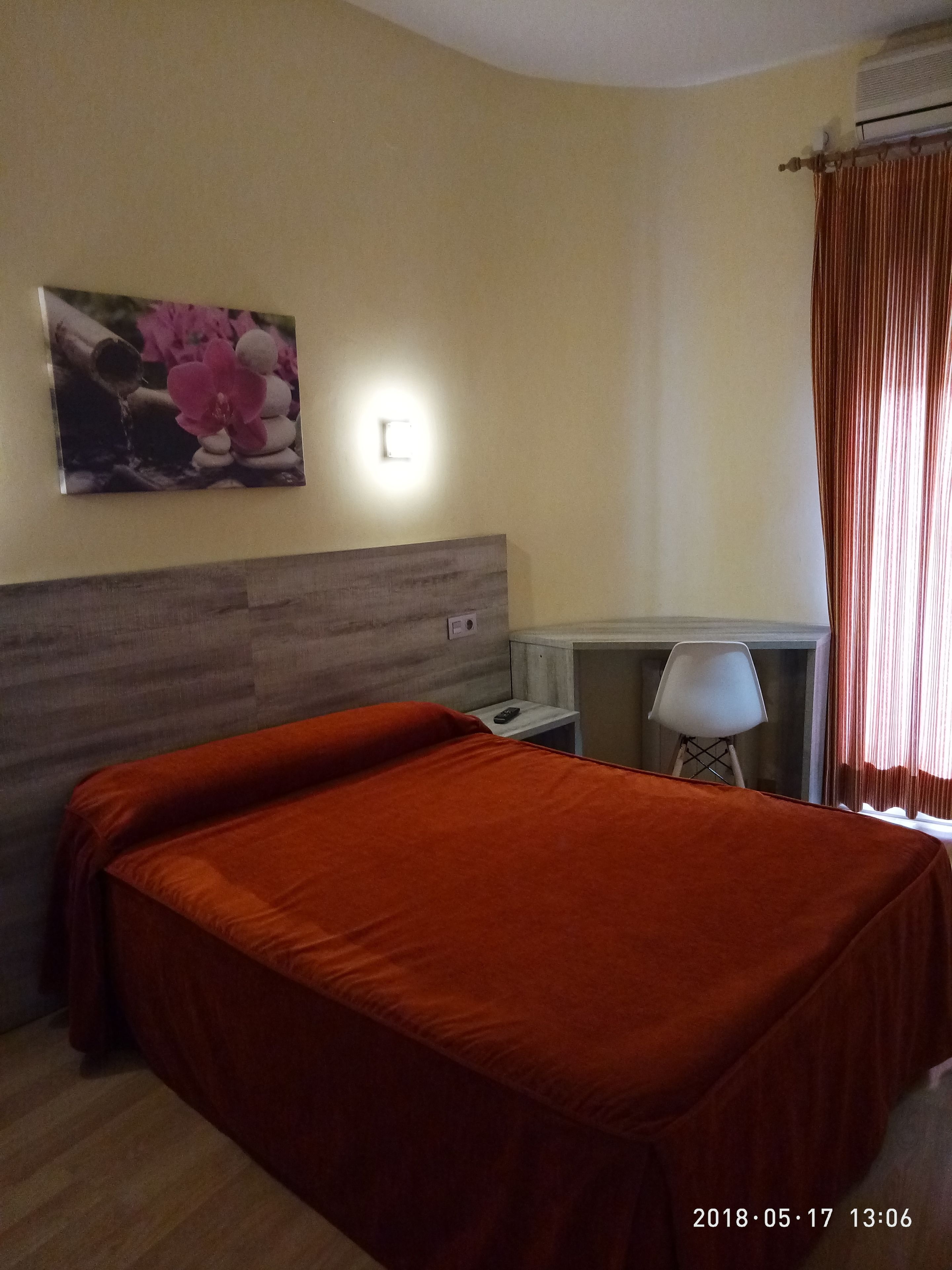 Une chambre d’hôtel avec un lit, une table de chevet, une lampe et un tableau au mur.