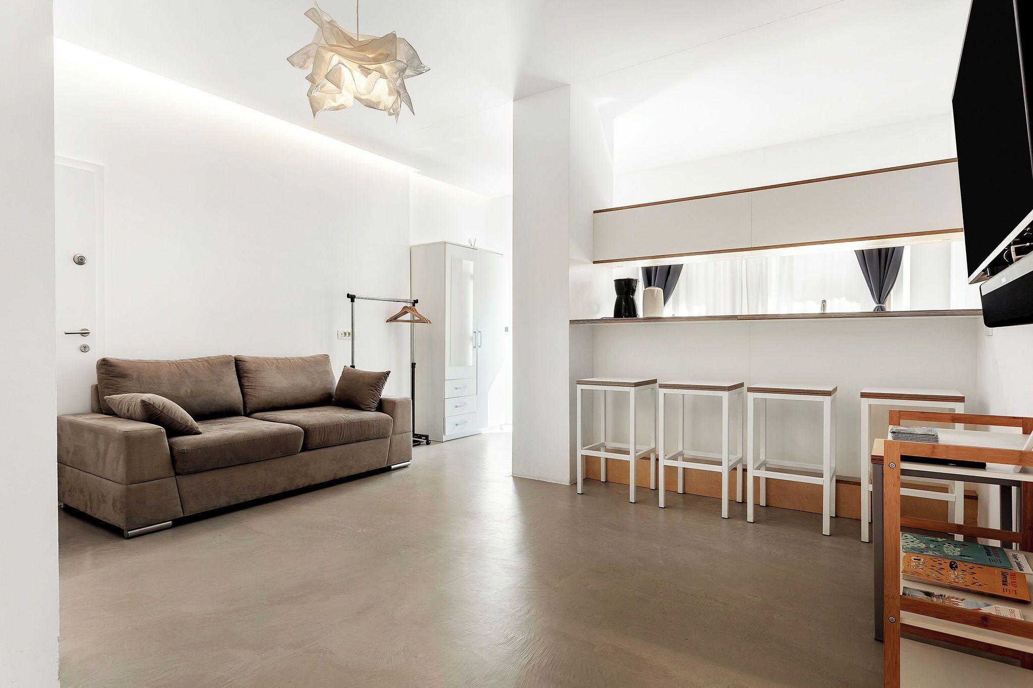 A modern living room with a sofa, a hanging light fixture, and a white wardrobe.