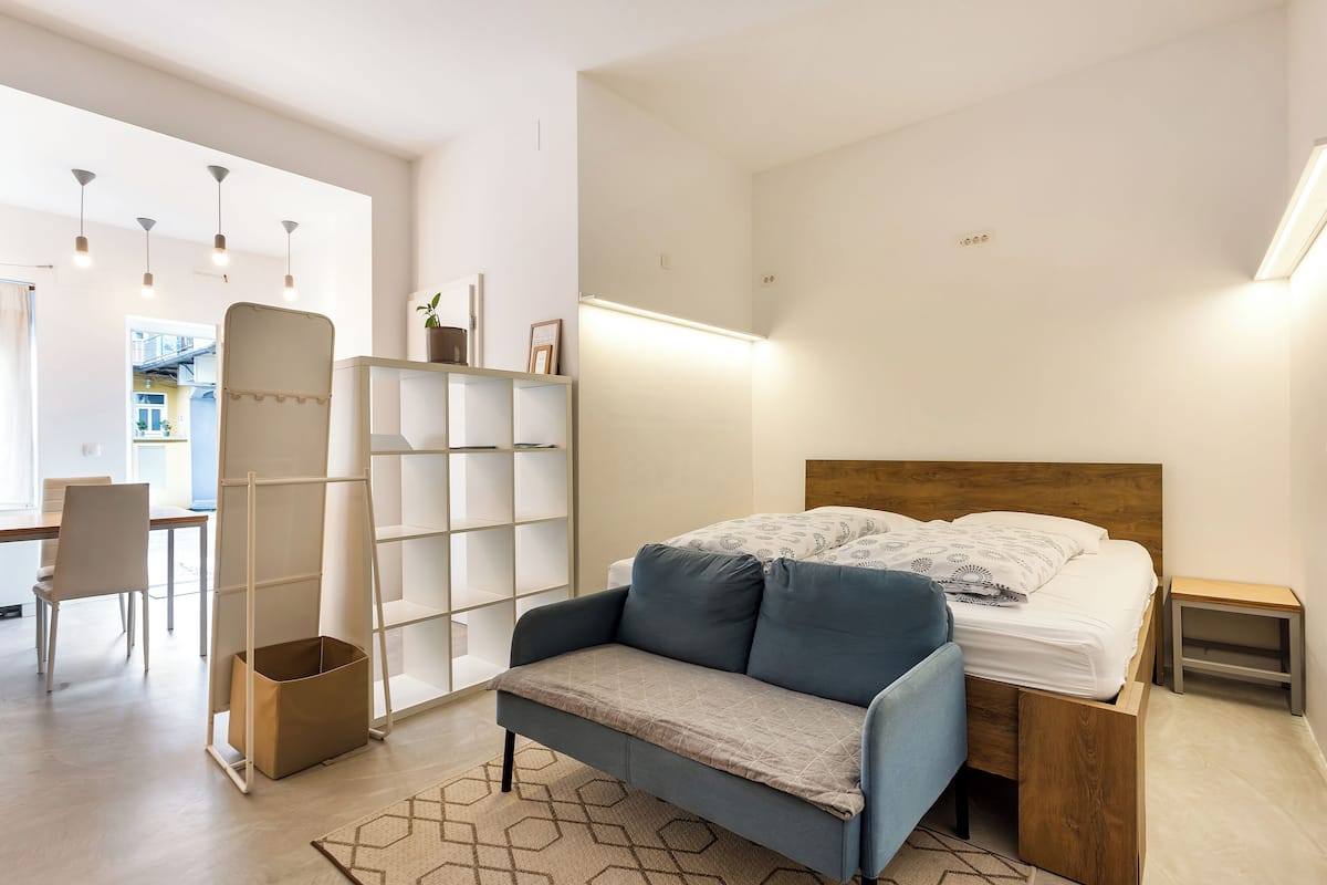 Une chambre moderne comprenant un lit, un canapé, un bureau et une étagère.