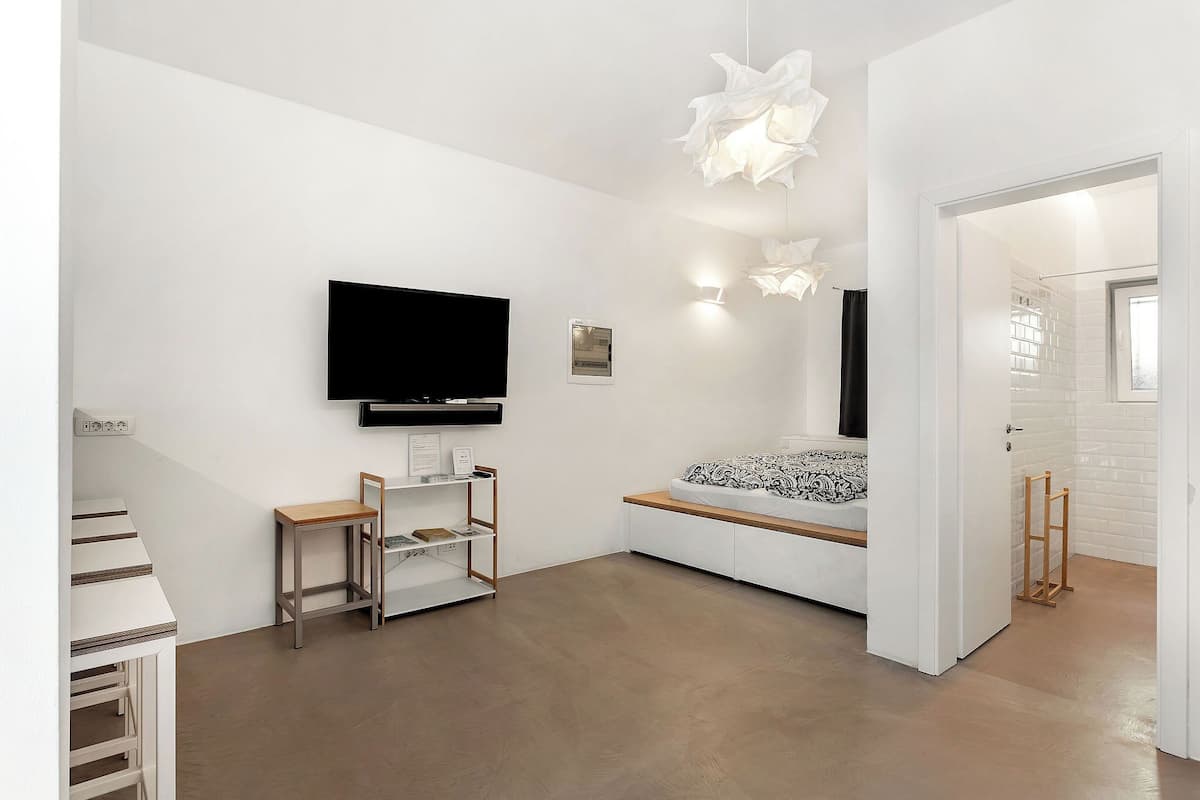 Un salon moderne doté d’un téléviseur à écran plat, de murs blancs et d’un aménagement minimaliste.