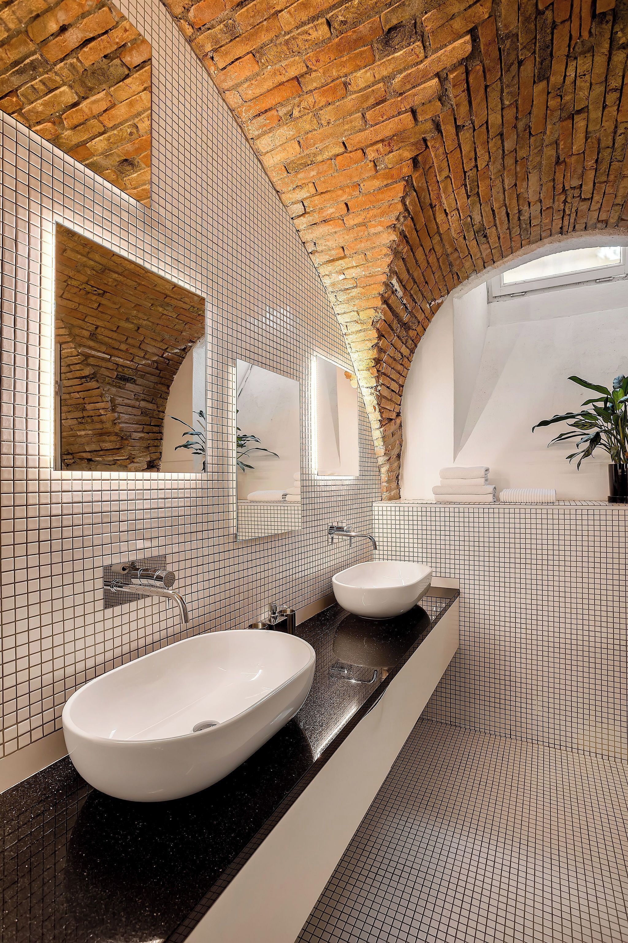 A bathroom with a white sink, a mirror, and a tiled wall.