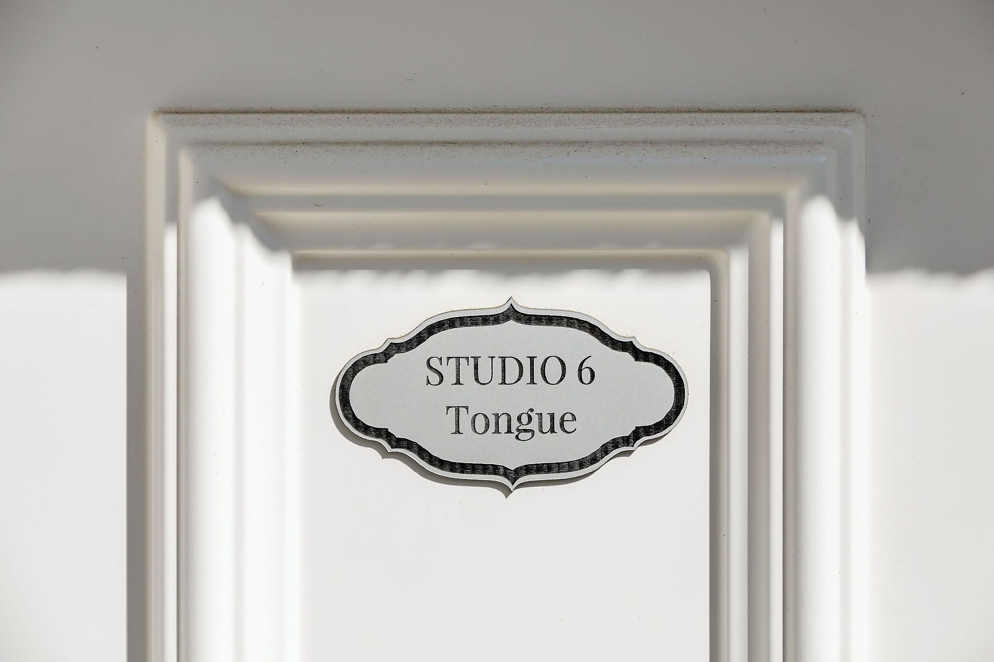 Ein Schild mit dem Text "STUDIO 6 Tongue" in einer verzierten Rahmen.