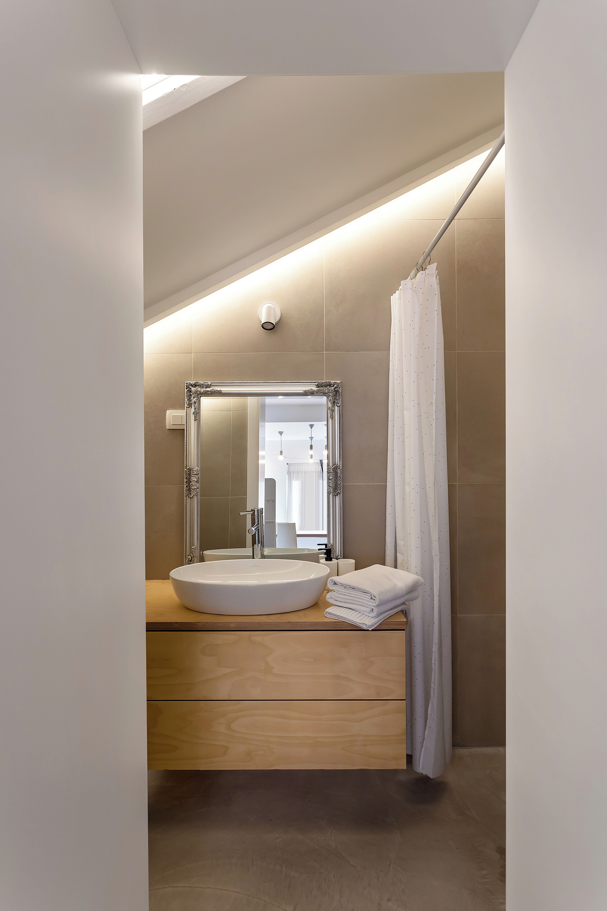 A modern bathroom with a large mirror, a round sink, and a wooden vanity.