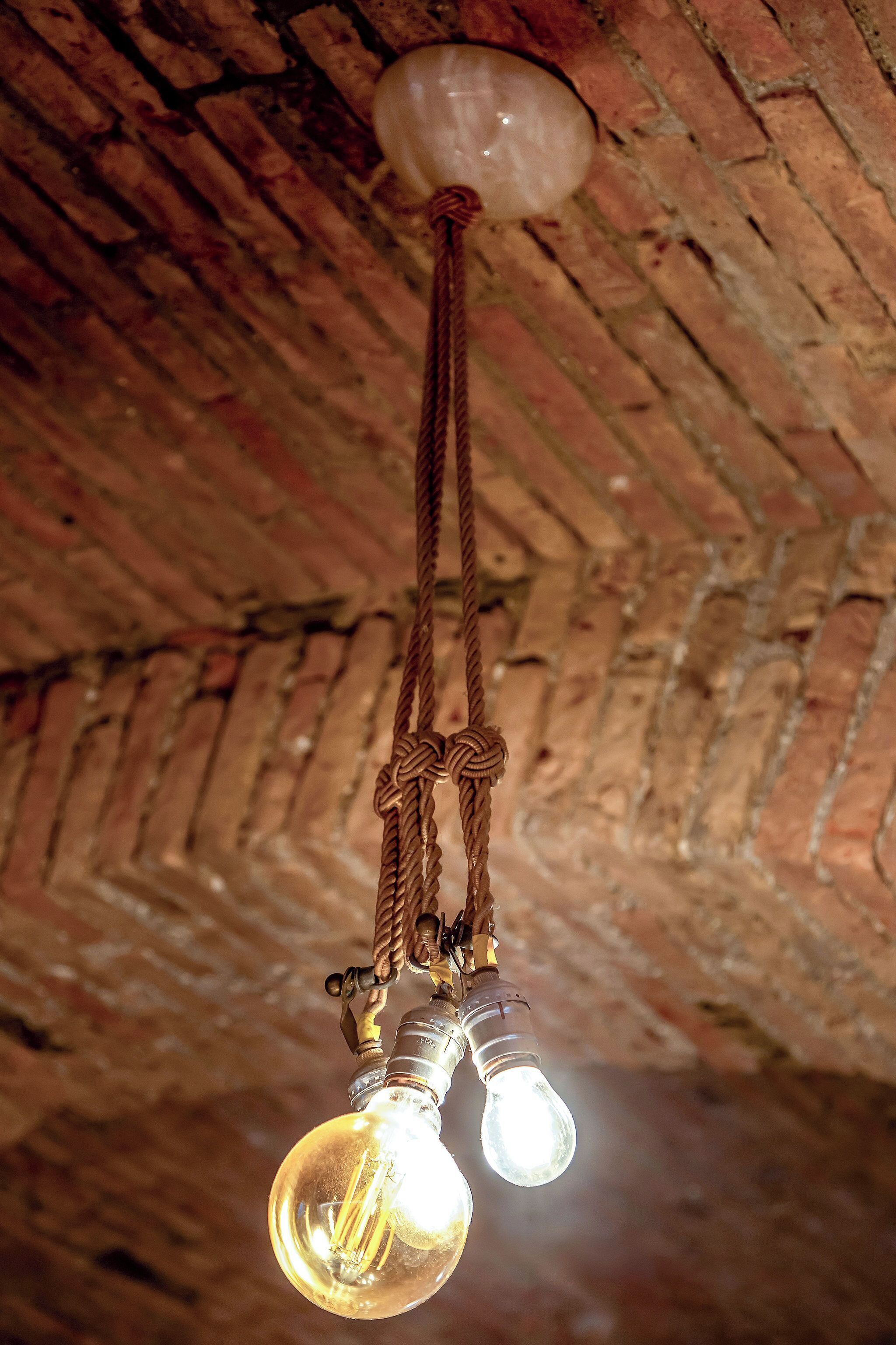 A ceiling with exposed brickwork and a hanging light fixture with two bulbs.