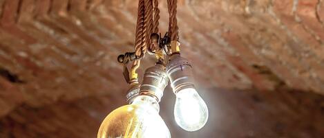 Un plafond avec des murs en briques apparentes et un luminaire suspendu doté de deux ampoules.