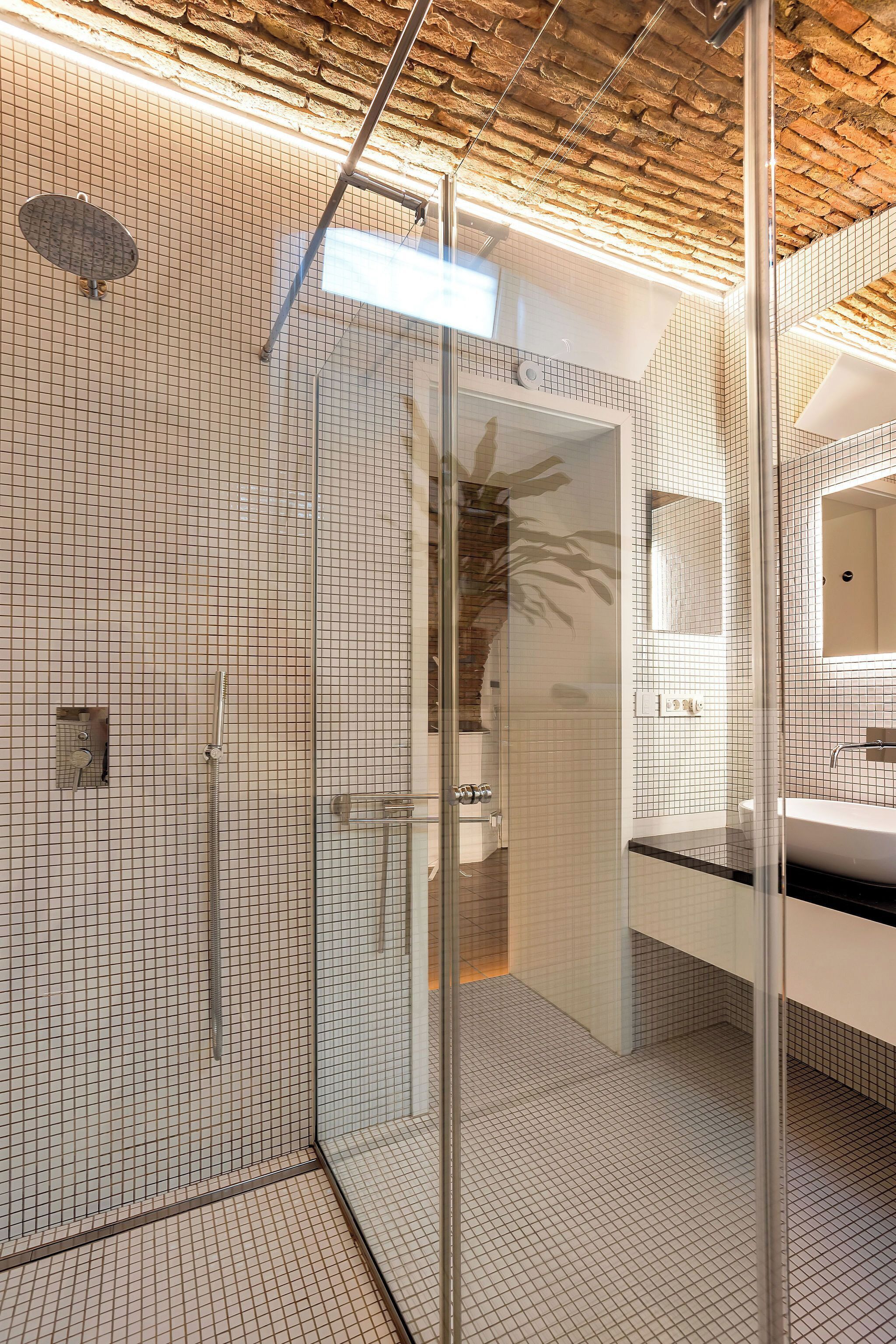 A modern bathroom with a glass shower enclosure, tiled walls, and a visible sink area.