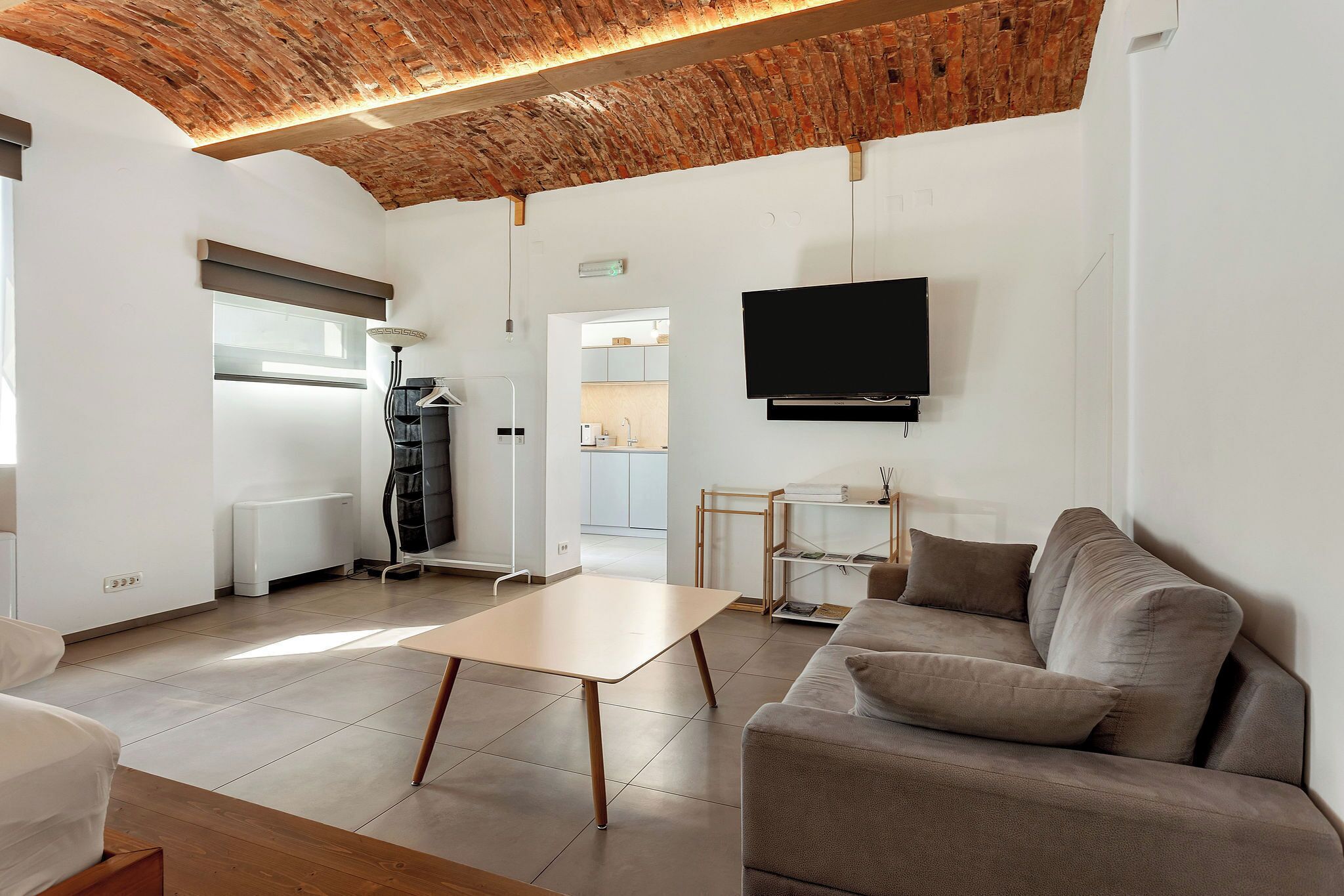 Uma sala de estar moderna com teto de tijolos, televisão de tela plana, sofá e mesa de jantar.